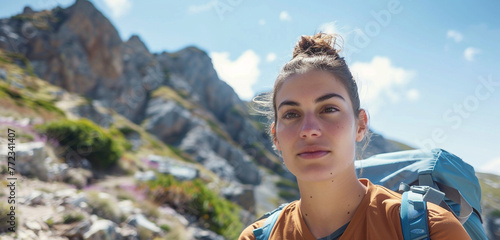 A woman hiking and admiring the breathtaking mountain view, her eyes meeting the camera with a mix of gratitude and amazement photo