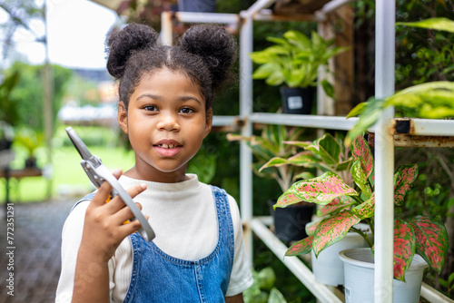 African American kid holding secateurs while working in her garden after school for weekend activity and outdoor education concept photo