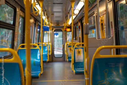Inside view of a vacant public transport vehicle featuring yellow grab handles and blue seats with selective focus.