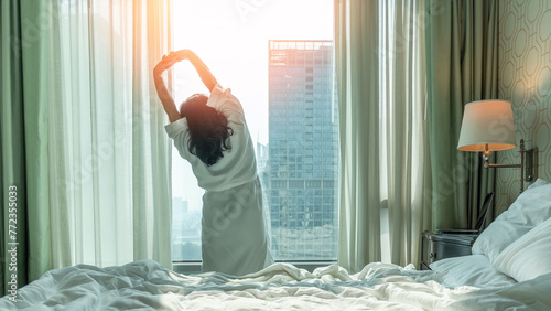 Work-Life balance, life quality, work and travel concept with businesswoman stretching in rest, relaxing, take it easy in modern hotel guest room or luxury home living room with notebook and city view photo