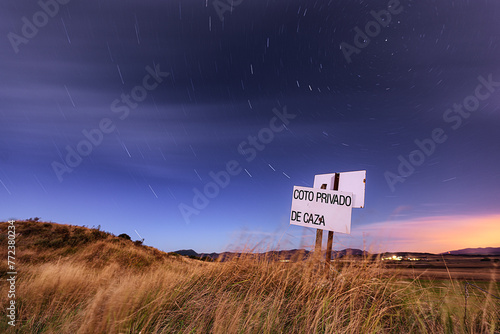 Night view with a starry sky of a field in Castilla, in the province of Burgos with a sign indicating a private hunting reserve