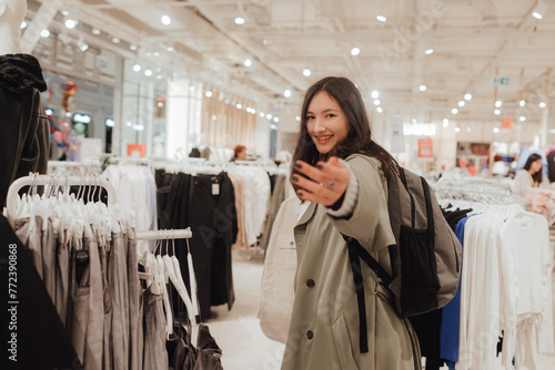 Korean teenage girl choosing and buying trendy clothes in a shopping mall. Retail and consumerism. Sale promotion and shopping concept. Part of a series
