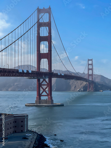 A cablestayed bridge spans across the glistening water with majestic mountains in the background, under a serene sky dotted with fluffy clouds. San Francisco, USA, California  photo
