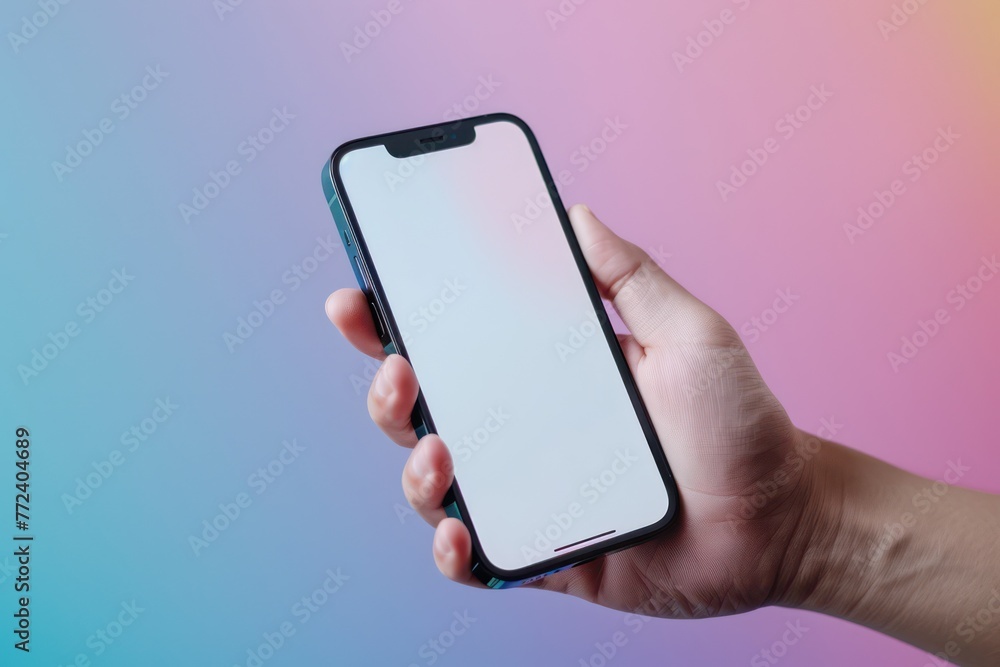 A person�s hand is shown holding a modern smartphone with a blank white screen, against a vibrant gradient background