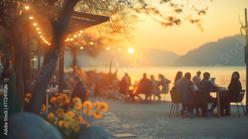People eating in atmospheric restaurant by the lake at sunset