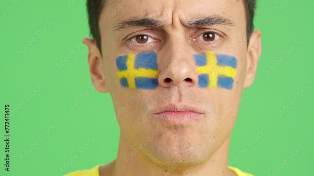 Serious man with a swedish flag painted on the face