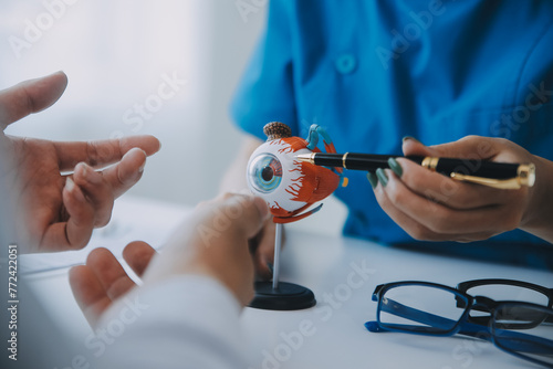Fotografie Close-up of Asian female doctor talking with elderly patient showing eyeball mod