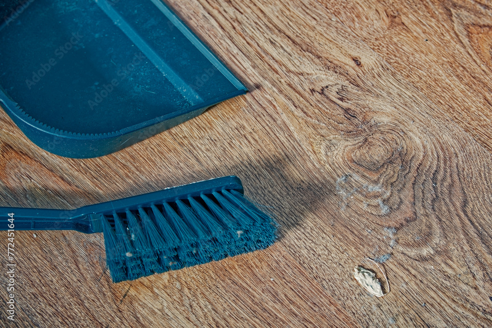 A dustpan and a brush for sweeping the floor lie on a wooden floor, there is a lot of dirt and dust on the brush, cleaning the room. - obrazy, fototapety, plakaty 