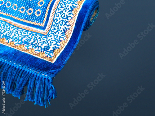 Folded Muslim prayer mat used to pay on dark background 