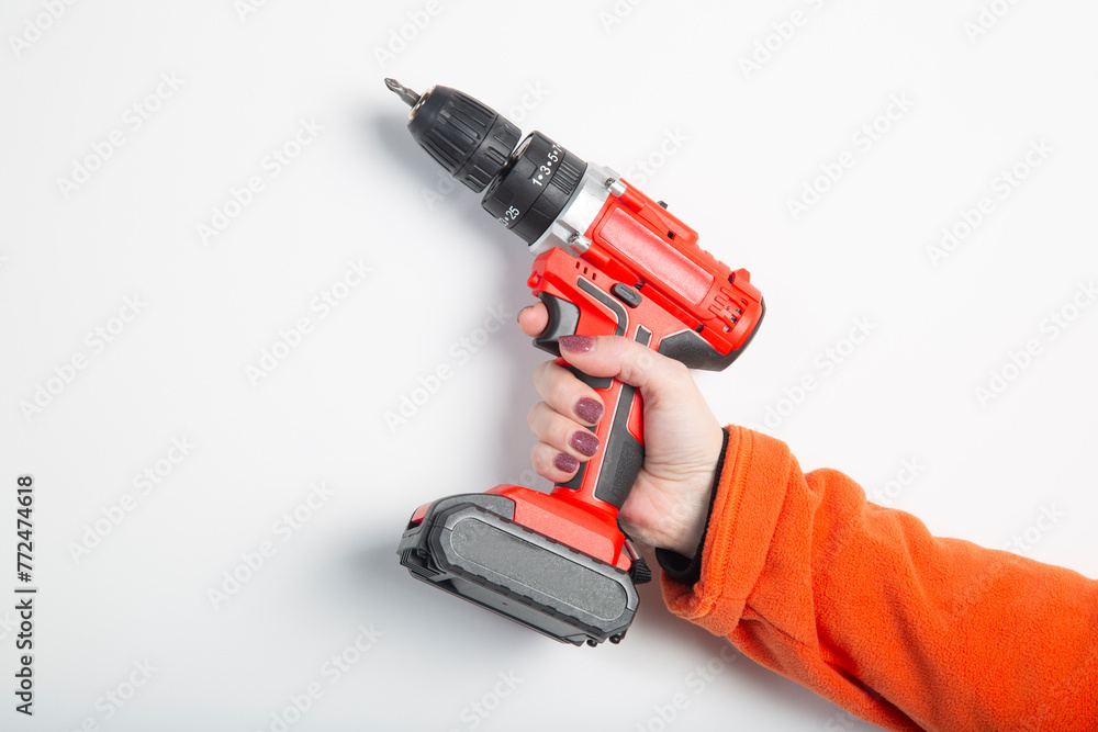 A portable cordless drill in the hands of a girl.A tool for the job . A portable cordless drill in the hands of a girl.A tool for the job .