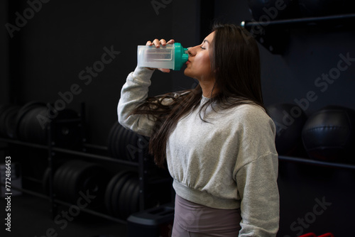 Close up of a woman taking protein from her shaker at the gym