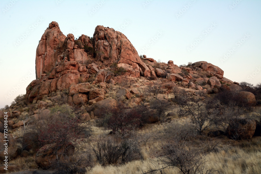 Fototapeta premium A rocky hill in a rocky arid terrain under a blue sky. Desert landscape and nature