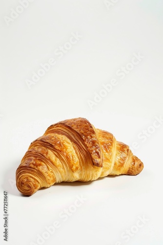A buttery croissant delicately balanced on a clean white surface