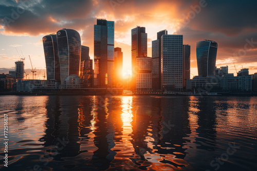 The sun is setting over a city skyline, casting a warm glow on the buildings