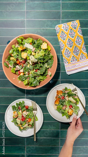 Chicken Caesar salad served on plate with a colorful napkin on a green tiled surface