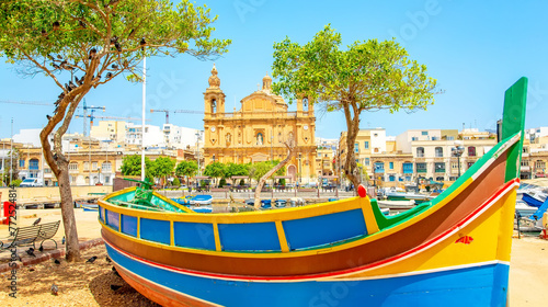 Maltese traditional colorful boat and Msida Parish Church on background, Malta