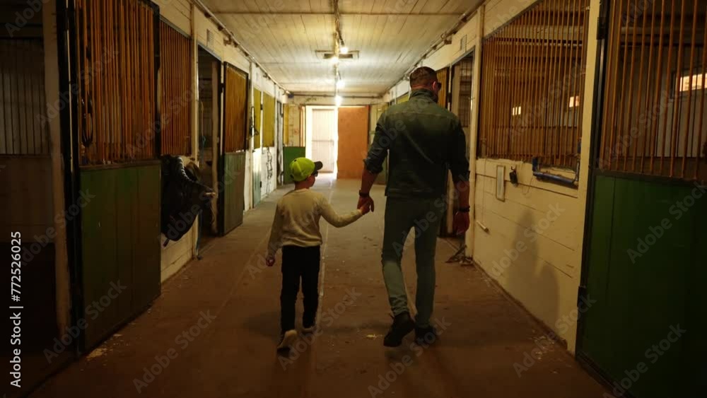 Father and son in stable corridor. Take walk around stables. Concept of peaceful unity Father and son in stable corridor. Take walk around stables. Concept of peaceful unity