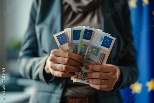 Businesswoman holding euro bills with blurred european union flag background, copy space for text photo