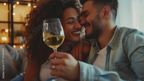 A young couple toasts with white wine in the living room