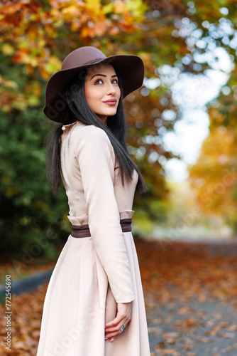 Urban elegance meets natural beauty. Trendy woman with shining eyes gazes up amongst autumn's beauty