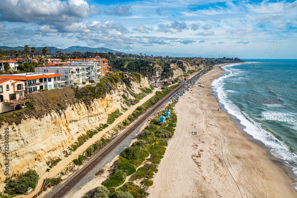 Aerial View of San Clemente Coastline With Lush Bluffs, Railroad Tracks, and Crashing Waves on a Sunny Day