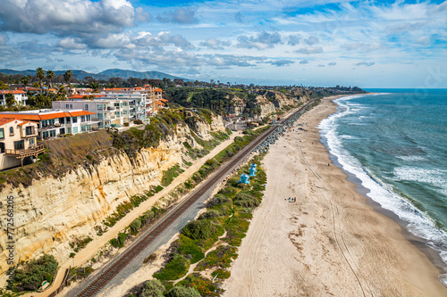 Aerial View of San Clemente Coastline With Lush Bluffs, Railroad Tracks, and Crashing Waves on a Sunny Day