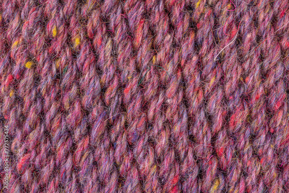 A close up of a purple and yellow yarn. The yarn is knotted and has a fuzzy texture A close up of a purple and yellow yarn. The yarn is knotted and has a fuzzy texture