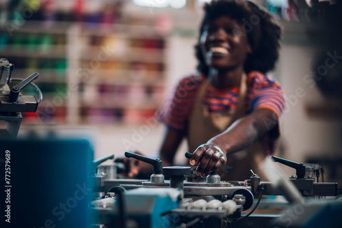 Close up of interracial printing shop worker adjusting printing press.