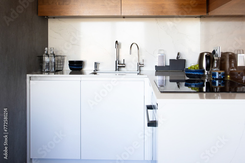 Kitchen brass utensils, chef accessories. Hanging modern kitchen with white marble wall and stone tabletop. © KatrinaEra