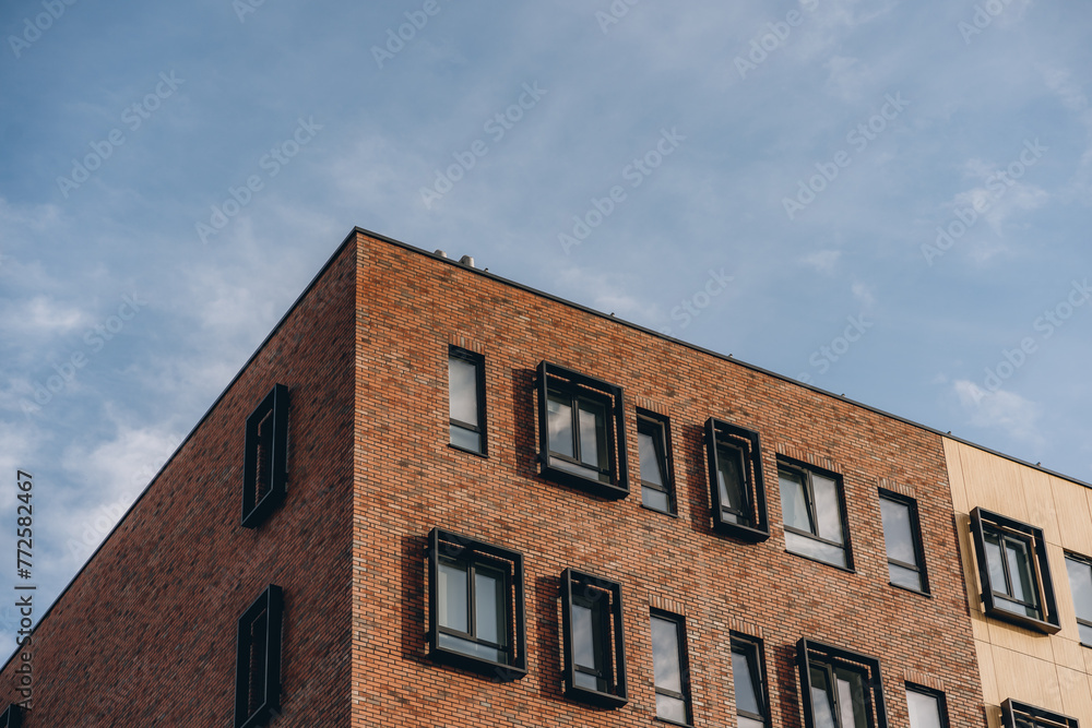 Brick brown wall of modern building facade, office or residential house under blue sky Brick brown wall of modern building facade, office or residential house under blue sky