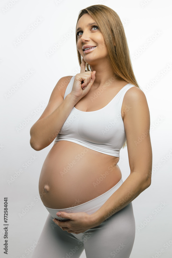 Blonde pregnant woman in white clothes looking thoughtful Blonde pregnant woman in white clothes looking thoughtful