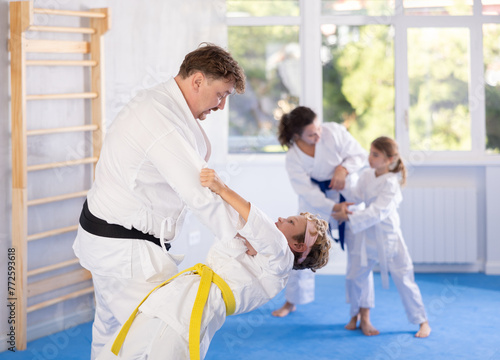 Parent with child athletes in white kimonos practice Brazilian jiu Jitsu Aikido Wing chun wrestling. Training at Academy of Martial Arts martial arts hand-to-hand combat.