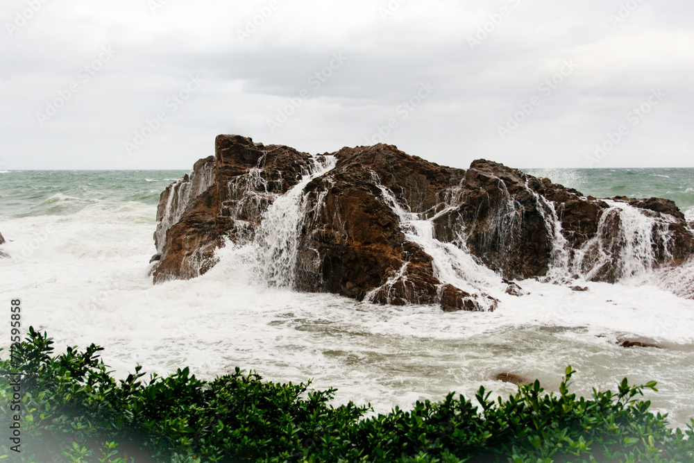 Obraz premium Immense sea rock covered by a large wave. Force of nature.
