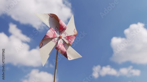 50 Pound Sterling banknote cut into windmill toy spinning over blue sky photo