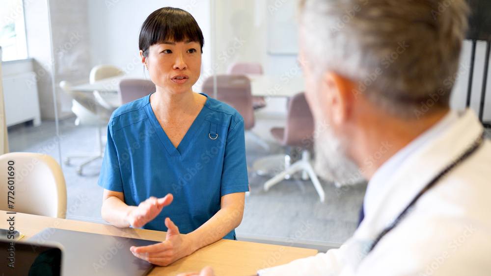 Japanese nurse and an older doctor having a meeting at the hospital office Japanese nurse and an older doctor having a meeting at the hospital office