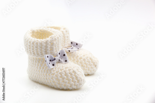 White crochet baby booties with black polka dot bows isolated on a white background. Handmade baby booties. Photo in high quality