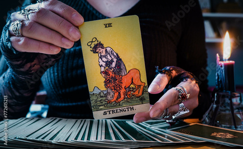 Malmö, Sweden - April 1, 2024: Strength Major Arcana Tarot Card Rider Waite Smith. Spiritual altar, Divination tool, witchcraft, healing crystals, fortune telling cards, cartomancy. photo