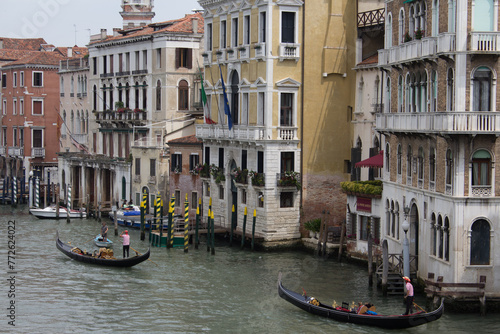 Gondoliers navigate the serene waters of a Venice canal, their gondolas gliding past historic palazzos under the watchful eyes of Italianate balconies and windows. photo