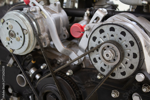 Close-up of a complex engine timing belt system, showcasing pulleys and gears on a black engine block, a testament to intricate automotive design
