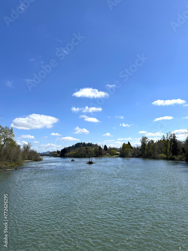 The Willamette River in Eugene, Oregon, on a spring day with blue sky and puffy white clouds. © GinaEPhoto