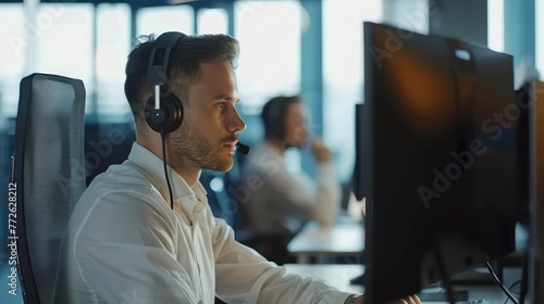 Serious businessman in headphones working on computer in office. Side view of handsome young man. Business concept