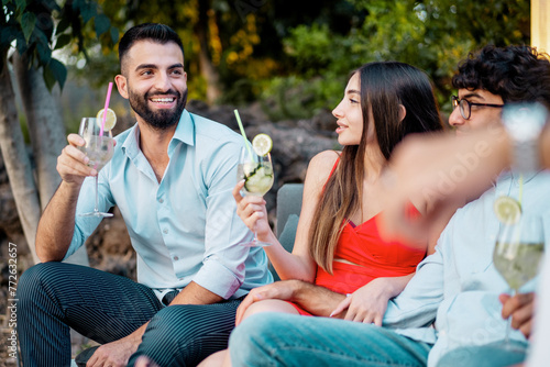 Young adults toast with stylish cocktails, enjoying a lively garden party, symbolizing carefree moments and friendship - group of friends cheering outdoors
