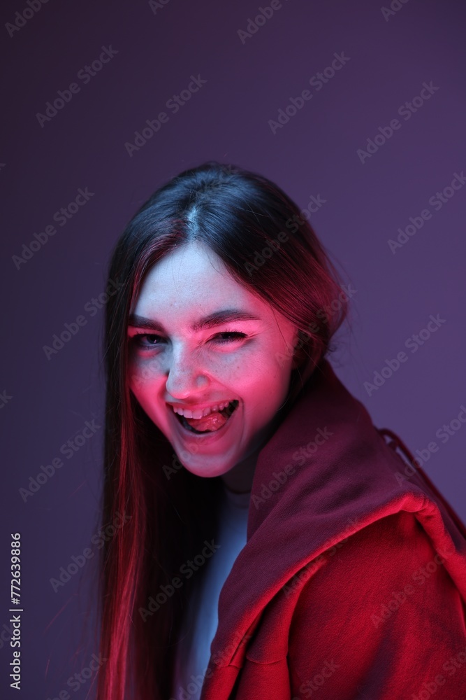 Portrait of happy woman on purple background in neon lights
