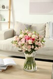 Beautiful bouquet of fresh flowers in vase on wooden table indoors