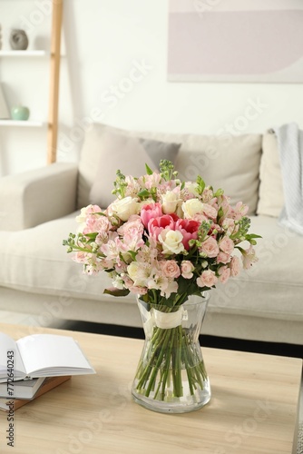 Beautiful bouquet of fresh flowers in vase on wooden table indoors © New Africa