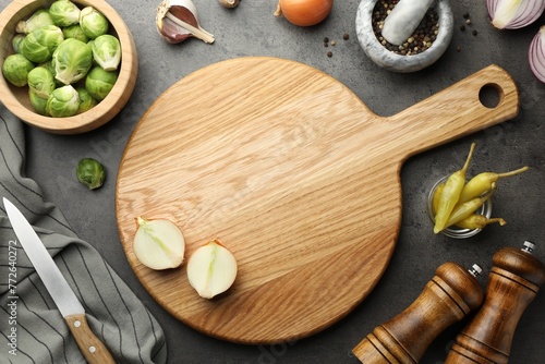 Flat lay composition with wooden cutting board and products on dark textured table