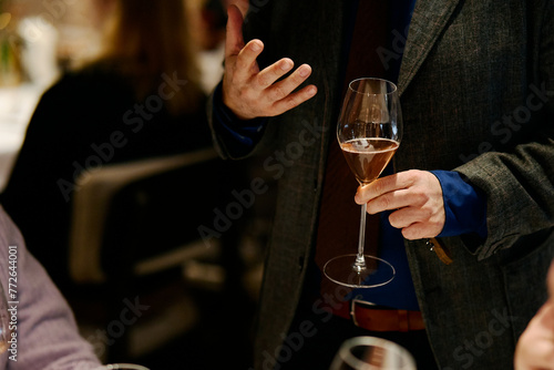 people hold glasses of white and red wine in a night restaurant, celebrating