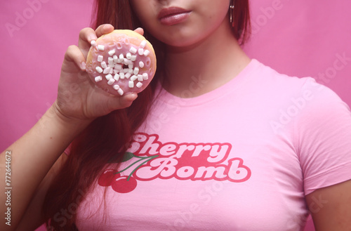 Young woman holding a pink tasty donut