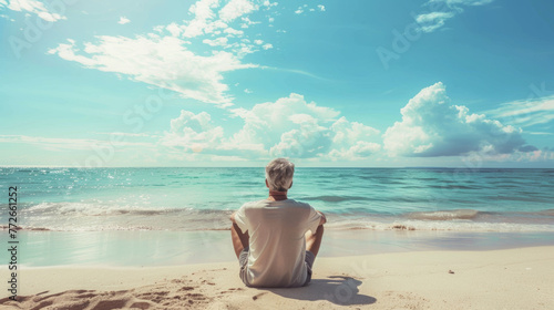 A lone man sitting on the beach  looking out to the sea  enjoying the quiet serenity of a sunny coastal landscape.