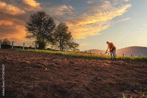 Farmer working on an agricultural fields at sunset.